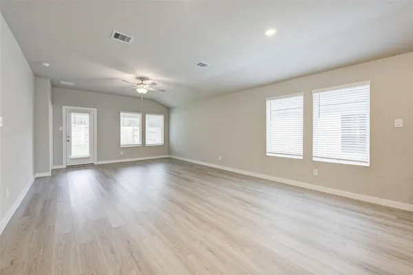 an empty room with wooden floor and windows