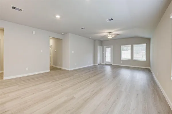 a view of an empty room with wooden floor and a window