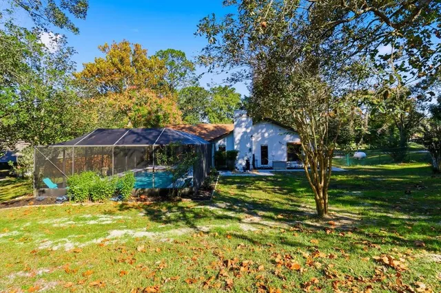 a view of house with outdoor seating and covered with trees