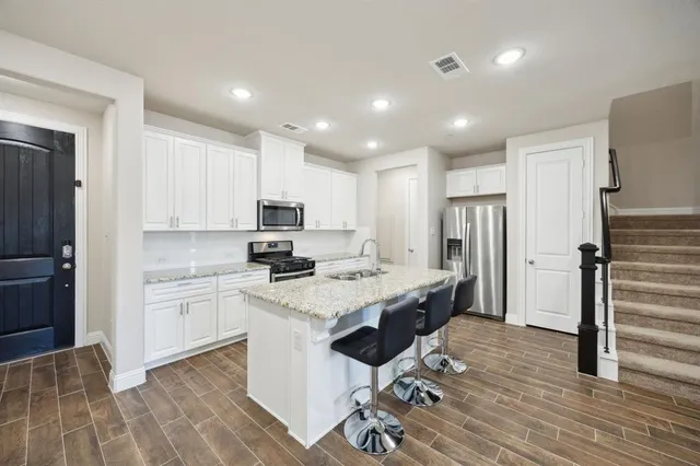 a kitchen with a sink a refrigerator and wooden floor