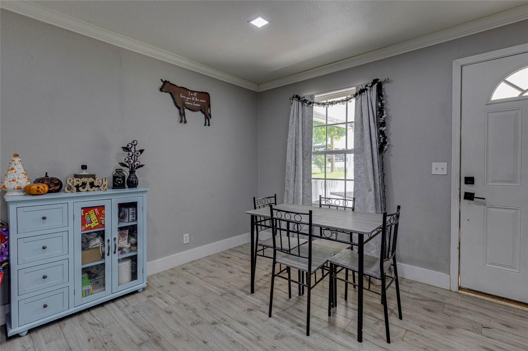 110 Avondale Road Anderson, SC 29624 - Photo 5 of 26 A cozy dining area features a simple table set for four, framed by crown molding and light wood flooring.
