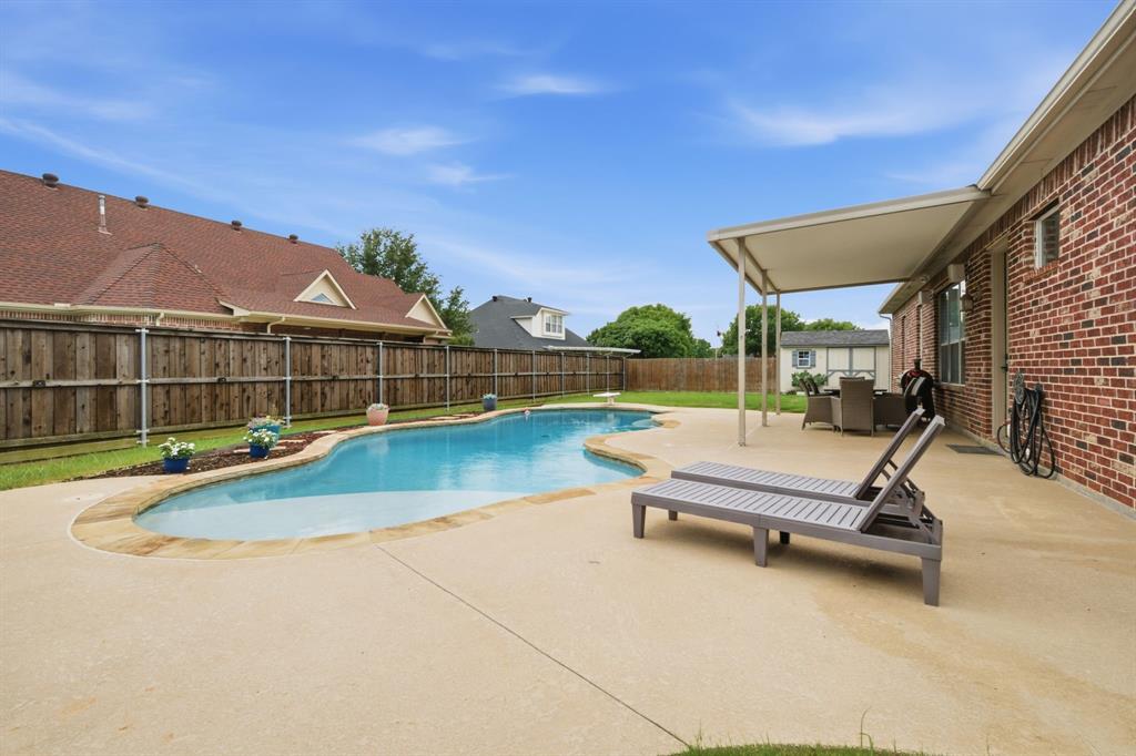603 Cedar Drive Pilot Point, TX 76258 - Photo 30 of 39 Inviting backyard featuring a freeform swimming pool with stone coping, an expansive concrete patio, and a covered patio area