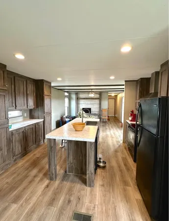 a room with stainless steel appliances kitchen island granite countertop a sink refrigerator and cabinets