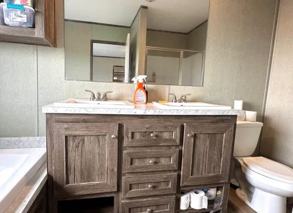 a bathroom with a granite countertop toilet sink and mirror