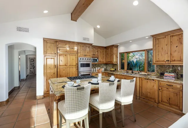 a dining hall with stainless steel appliances kitchen island granite countertop a dining table chairs and view living room