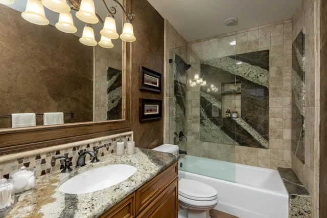 a bathroom with a granite countertop sink toilet mirror and bathtub