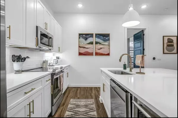 a kitchen with stainless steel appliances granite countertop a sink stove oven and white cabinets with wooden floor