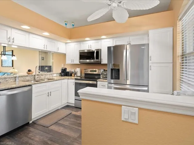 a kitchen with stainless steel appliances granite countertop a sink a stove a refrigerator a microwave oven with cabinets and wooden floor