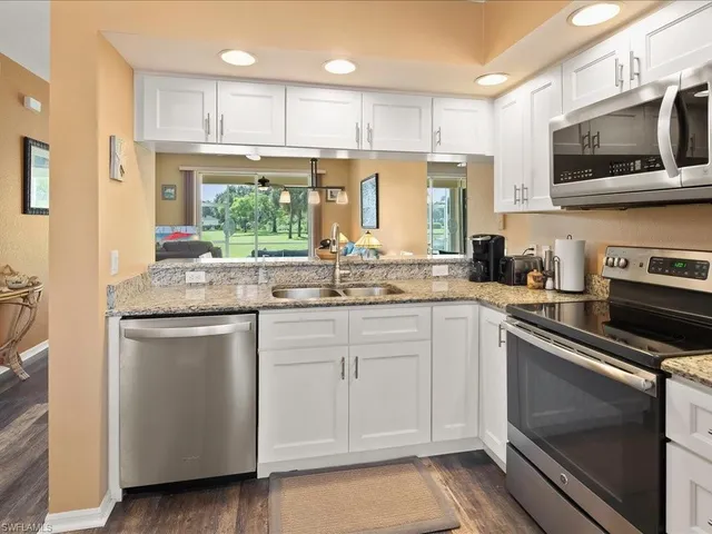 a kitchen with stainless steel appliances granite countertop a stove a sink and a microwave