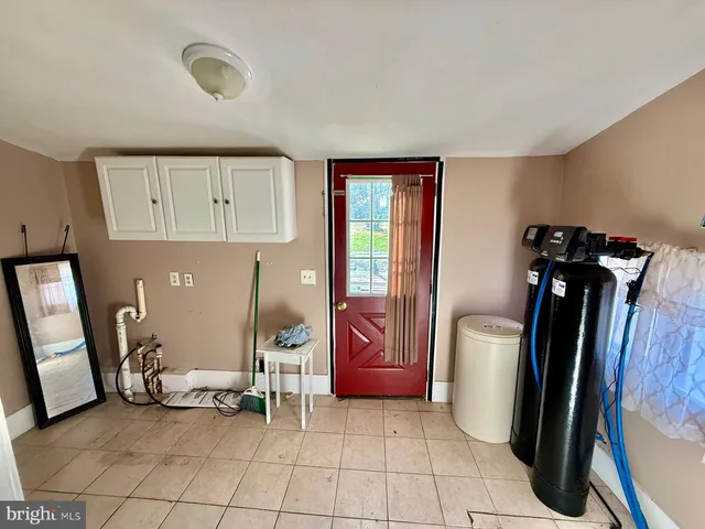 a living room with furniture a refrigerator and a mirror
