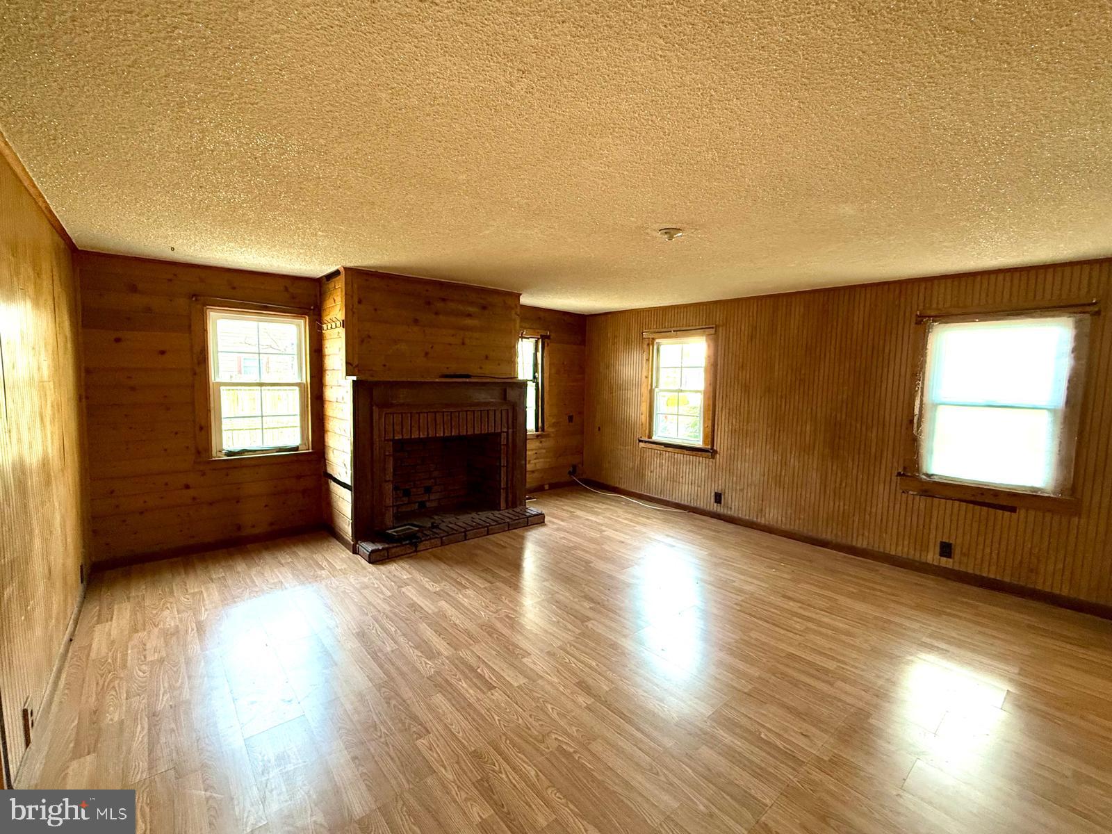 73 Maple Avenue Cedarville, NJ 08311 - Photo 4 of 25 an empty room with wooden floor and fireplace