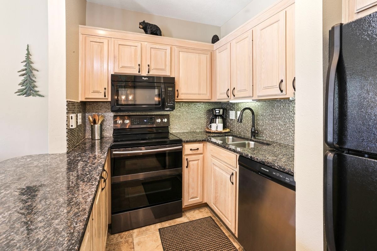 22138 Highway 6, Unit 1553 Keystone, CO 80435 - Photo 13 of 43 a kitchen with granite countertop a refrigerator stove and microwave