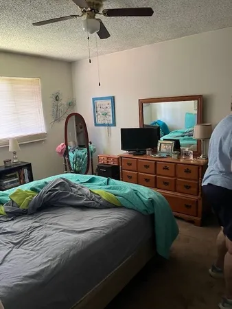 a bedroom with a bed and a flat tv screen on dresser