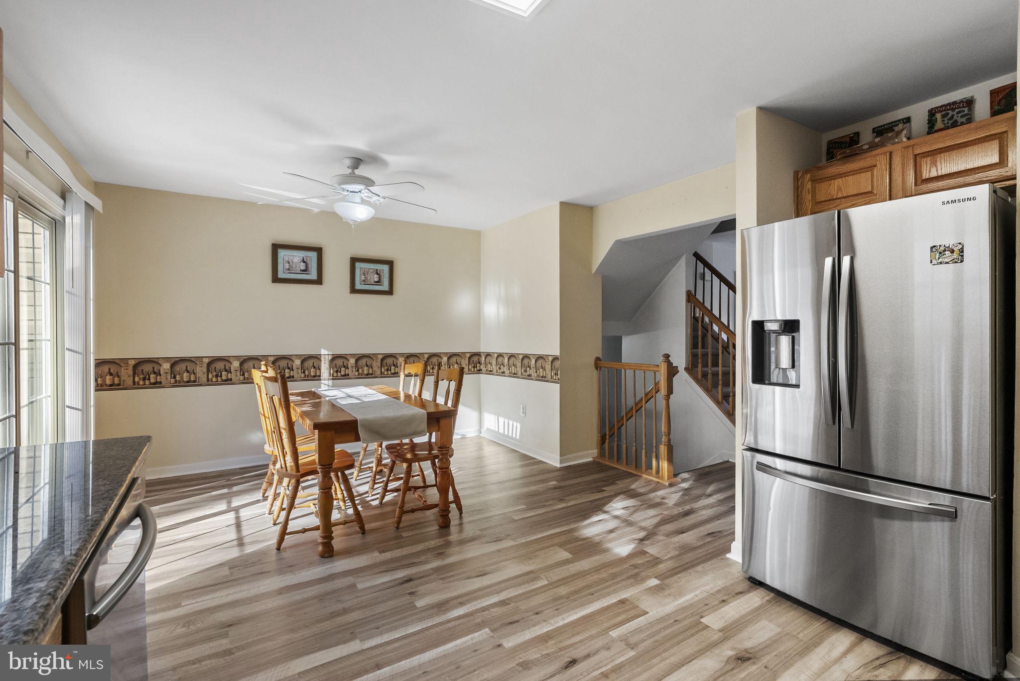 27 Branford Way Coatesville, PA 19320 - Photo 11 of 44 a kitchen with stainless steel appliances a refrigerator a stove a dining table and chairs with wooden floor