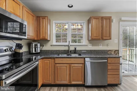a kitchen with granite countertop a stove sink and cabinets