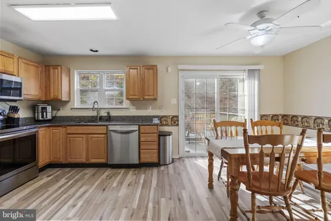 a kitchen with stainless steel appliances granite countertop a stove top oven a sink dishwasher a dining table and chairs with wooden floor