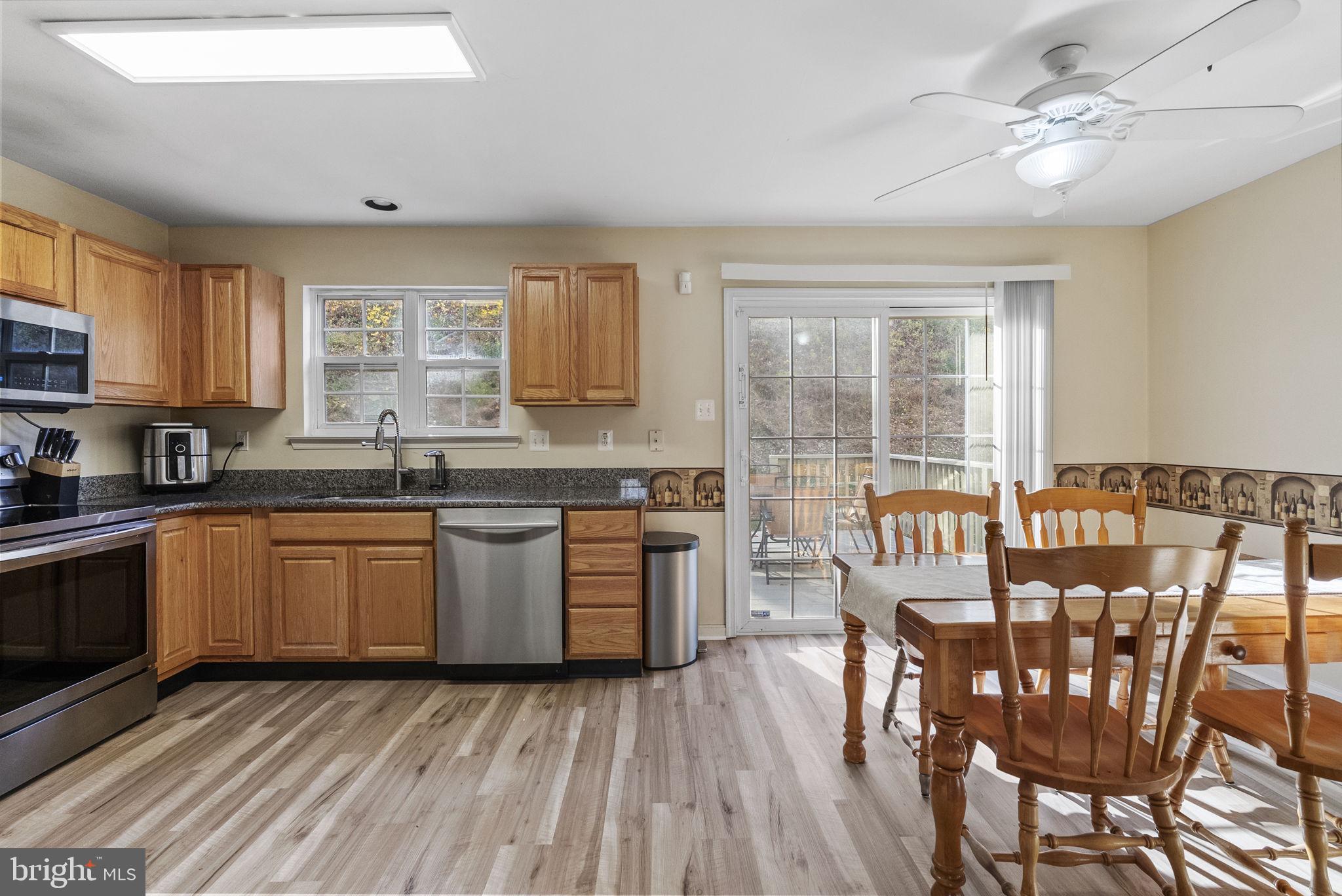 27 Branford Way Coatesville, PA 19320 - Photo 8 of 44 a kitchen with stainless steel appliances granite countertop a stove top oven a sink dishwasher a dining table and chairs with wooden floor