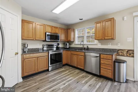 a kitchen with granite countertop wooden floors a stove top oven a sink and dishwasher with wooden floor