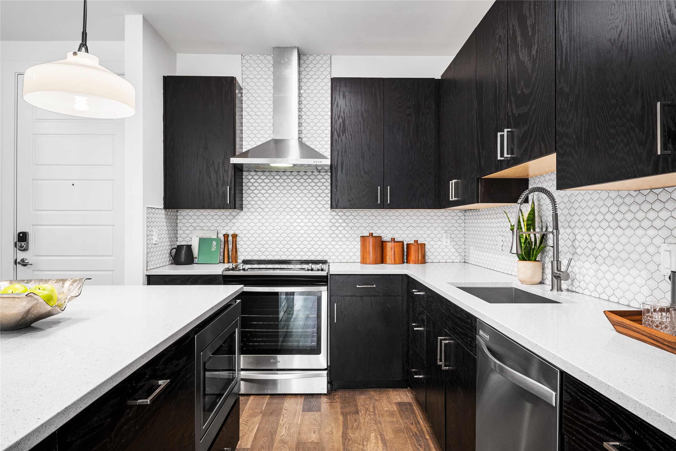 1615 East 7th Street, Unit 208 Austin, TX 78702 - Photo 5 of 30 Kitchen with dark cabinets, light stone counters, decorative light fixtures, and stainless steel appliances