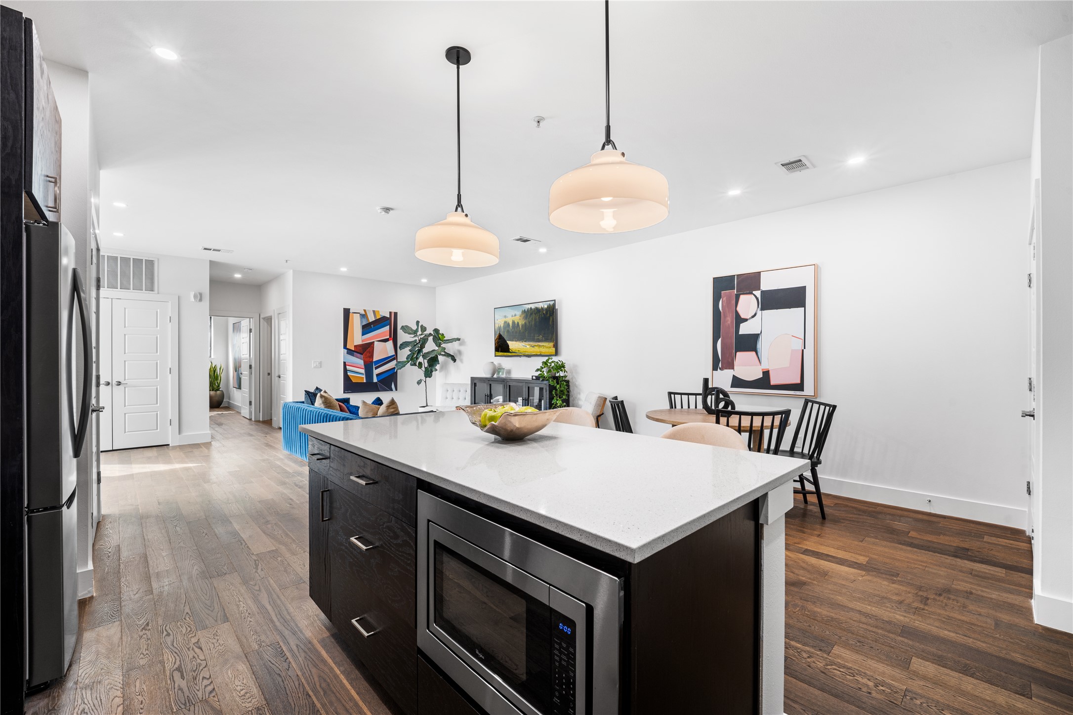 1615 East 7th Street, Unit 208 Austin, TX 78702 - Photo 6 of 30 Kitchen with dark cabinetry, decorative light fixtures, stainless steel appliances, light stone countertops, and dark wood-type flooring