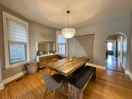 a dining room with wooden floor table and chairs