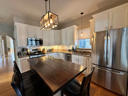 a kitchen with granite countertop a refrigerator a stove a sink dishwasher a dining table and chairs