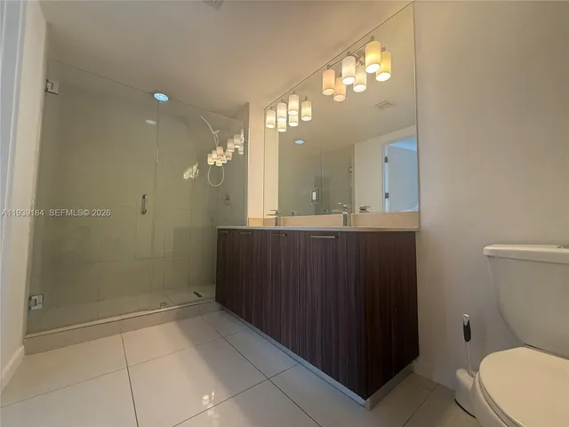 a bathroom with a sink a toilet a mirror and shower