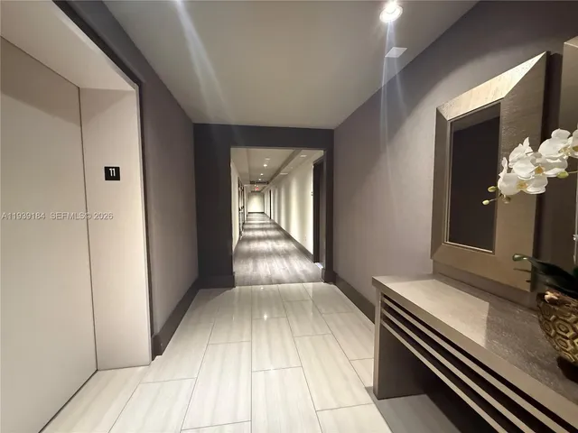 a view of a hallway with wooden floor and a flat screen tv