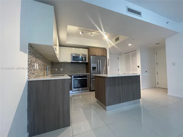 a kitchen with stainless steel appliances kitchen island granite countertop a refrigerator and a stove