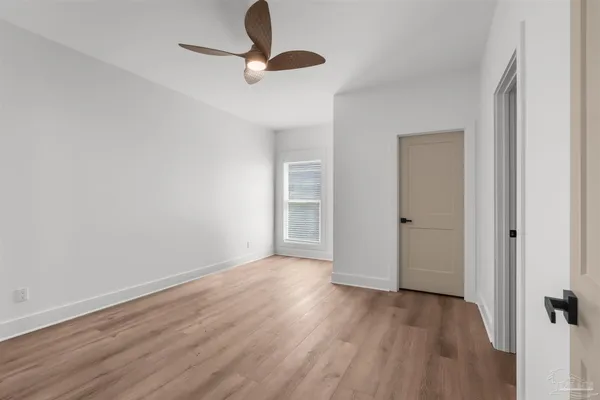 a view of an empty room with wooden floor closet and a window
