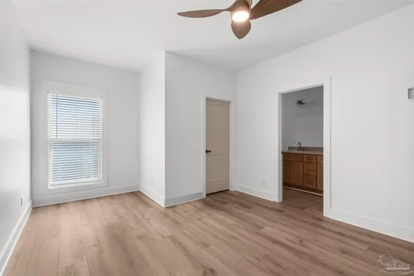 an empty room with wooden floor cabinet and windows
