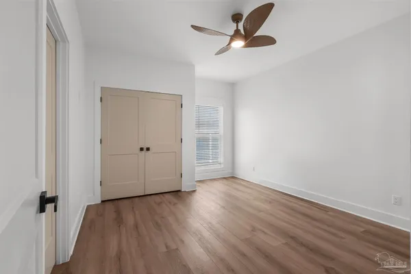 an empty room with wooden floor and a ceiling fan