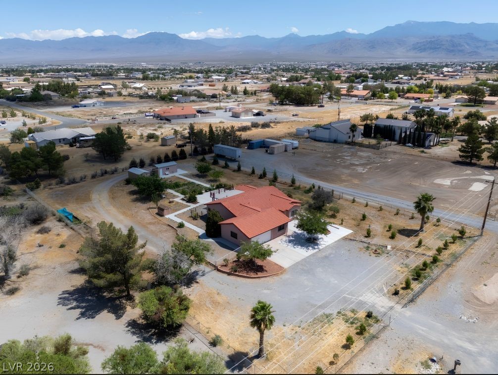 1220 East Gamebird Road Pahrump, NV 89048 - Photo 43 of 49 An aerial perspective showcases a vibrant desert home with a terracotta roof, framed by mature trees and mountain views.