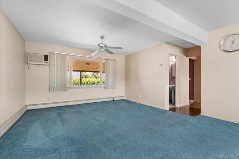 a view of an empty room with window and a kitchen