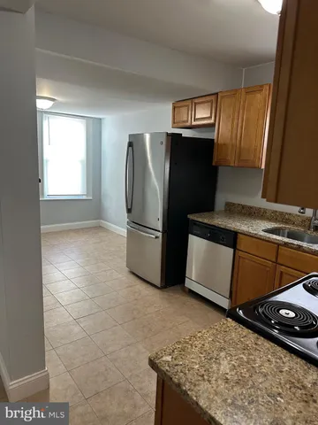 a kitchen with granite countertop a refrigerator and a stove top oven