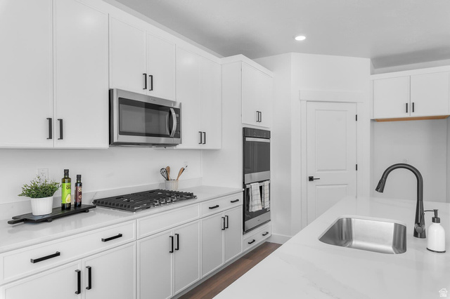 342 North Rhyolite Drive, Unit 88 Hurricane, UT 84737 - Photo 9 of 26 Modern kitchen featuring white cabinetry with matte black hardware, stainless steel appliances including an over-the-range microwave and built-in double oven, a gas cooktop, and light-toned countertops