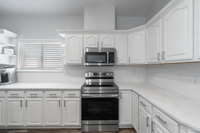 a kitchen with granite countertop white cabinets and stainless steel appliances