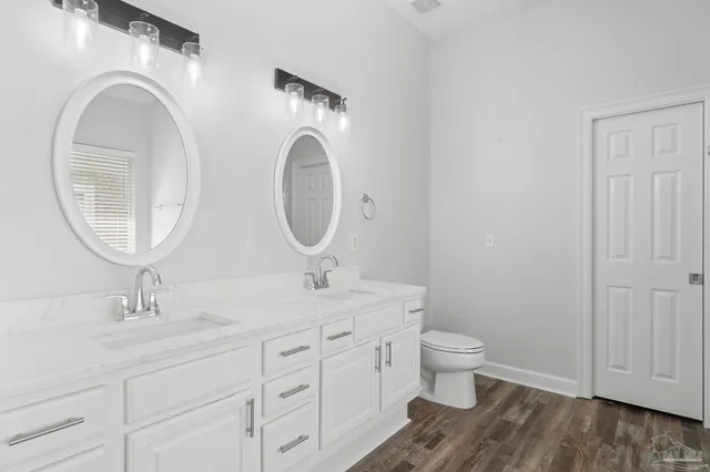 a bathroom with a granite countertop toilet a sink and a mirror