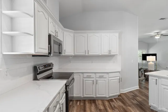 a kitchen with stainless steel appliances granite countertop a refrigerator a stove and white cabinets with wooden floor