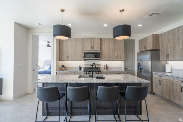 2972 West 570 North Hurricane, UT 84737 - Photo 25 of 104 Kitchen featuring light stone counters, a kitchen breakfast bar, and an island with sink