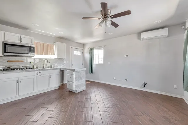 a kitchen with granite countertop a stove a sink and white cabinets with wooden floor