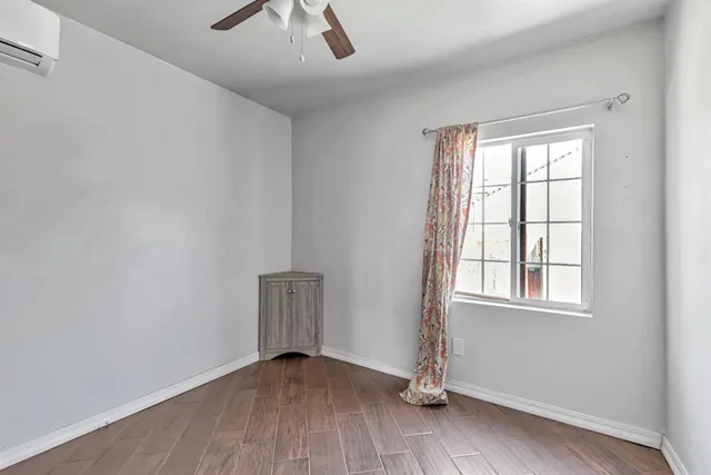 an empty room with wooden floor chandelier fan and windows