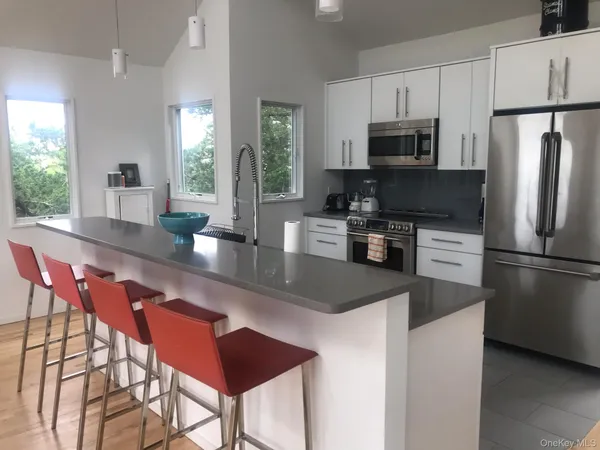 a kitchen with stainless steel appliances granite countertop a refrigerator a stove a sink a dining table and chairs