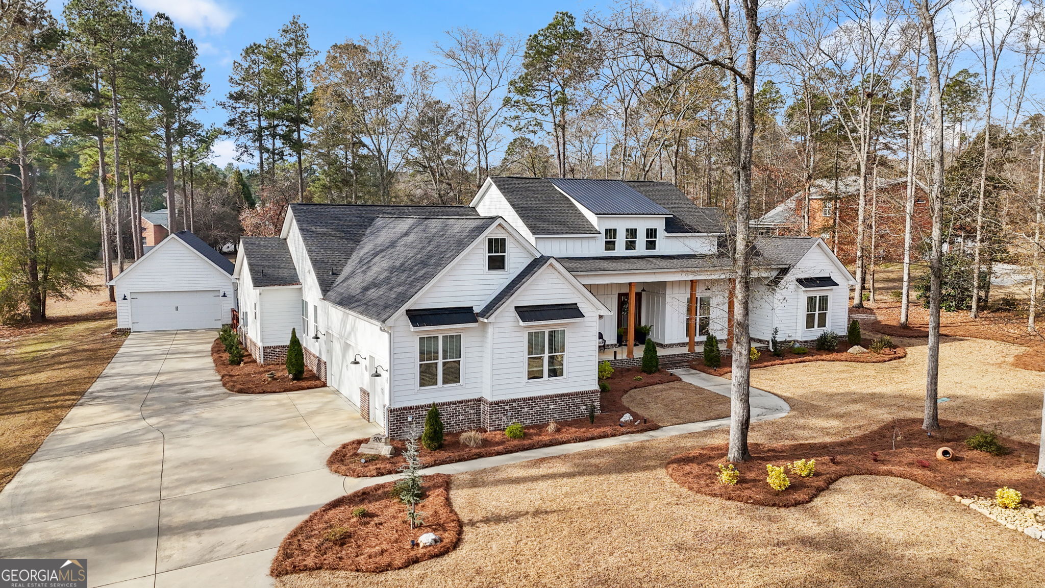 a view of a white house with large tree and wooden fence