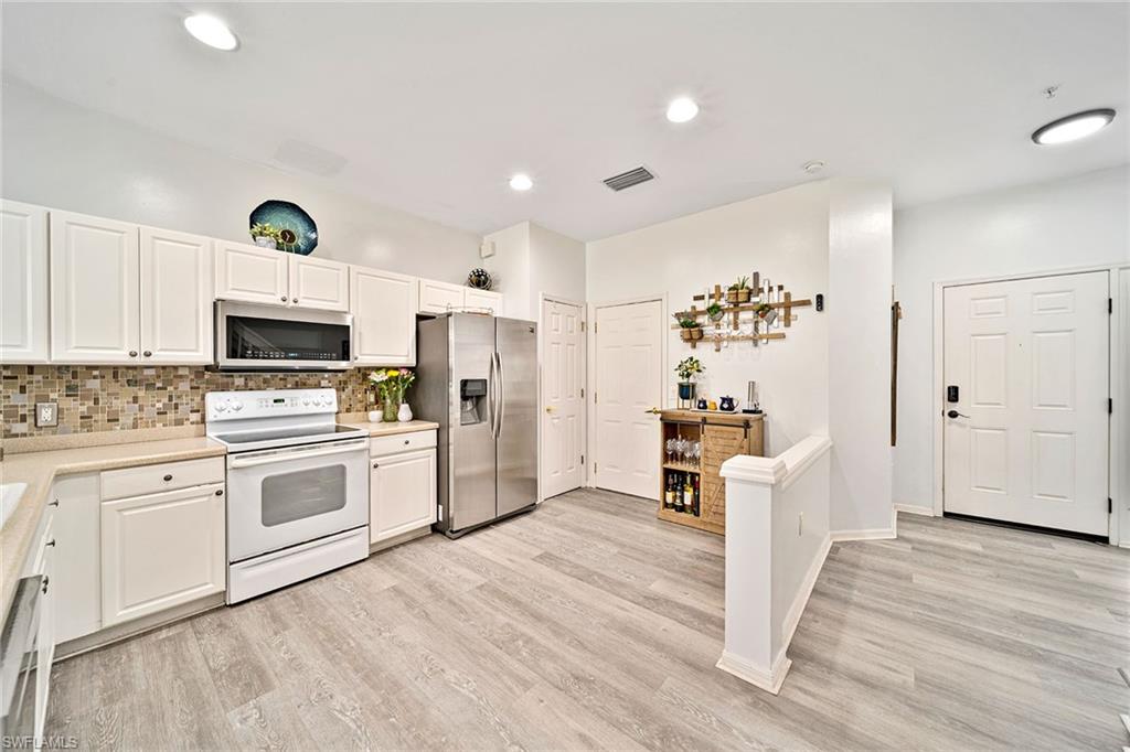 816 Hampton Circle Naples, FL 34105 - Photo 6 of 49 a kitchen with granite countertop a refrigerator oven a sink dishwasher and white cabinets with wooden floor
