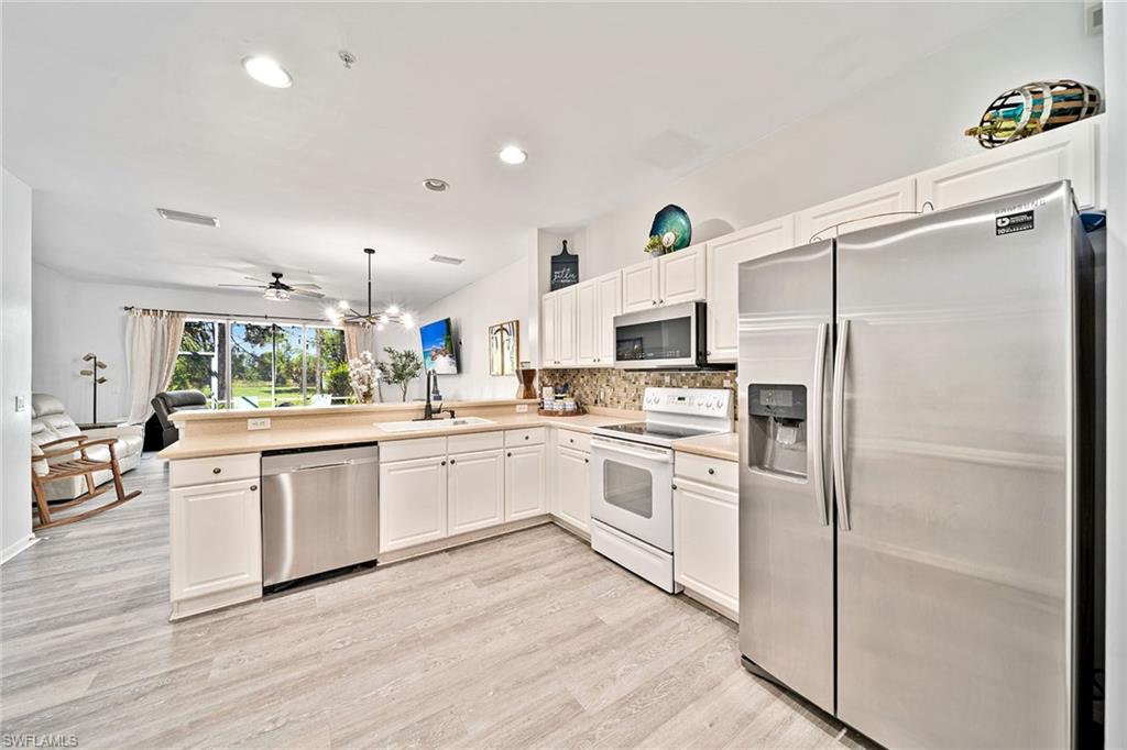 816 Hampton Circle Naples, FL 34105 - Photo 9 of 49 a kitchen with white cabinets and white appliances