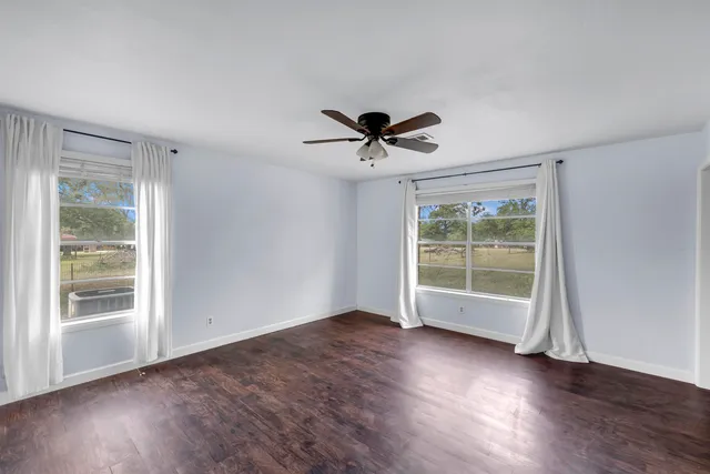 a view of an empty room with a window and wooden floor