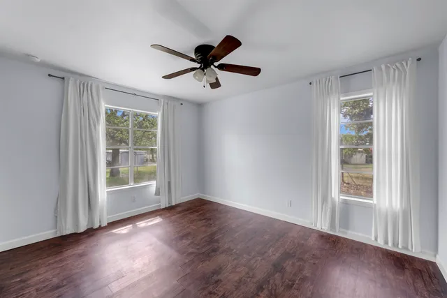 a view of empty room with wooden floor and fan