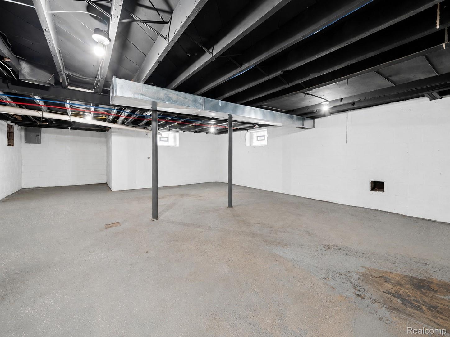 9175 Devonshire Road Detroit, MI 48224 - Photo 21 of 23 Spacious unfinished basement with painted concrete floor, white painted walls, and an exposed black painted ceiling with visible ductwork