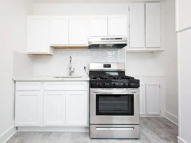a kitchen with stainless steel appliances granite countertop white cabinets and a stove